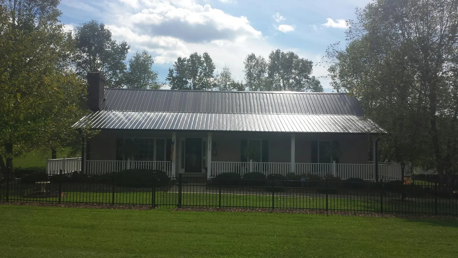 Gray metal roof on a brick ranch with a full width front porch — Gutter Guard Installation work by our crew in Lincoln City