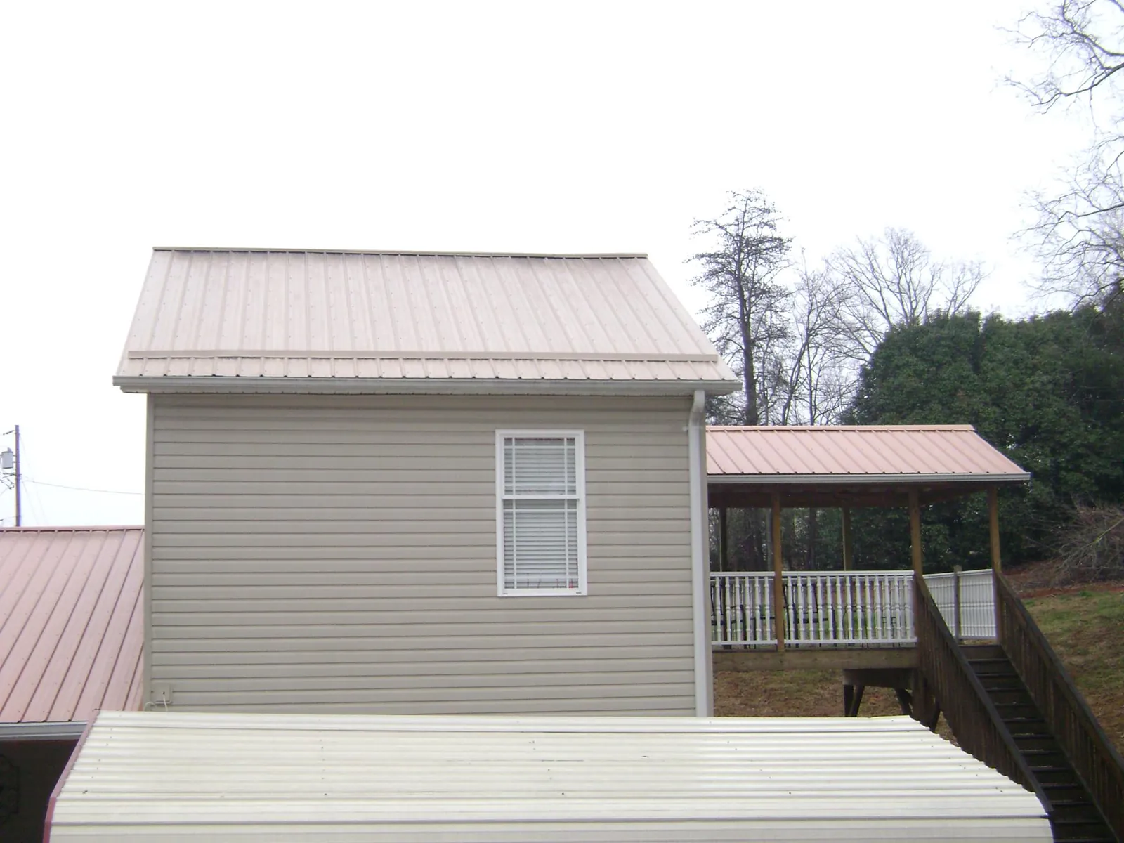 Tan metal roofs on a two story addition and attached porch, from a Roof Replacement job in Lincoln City