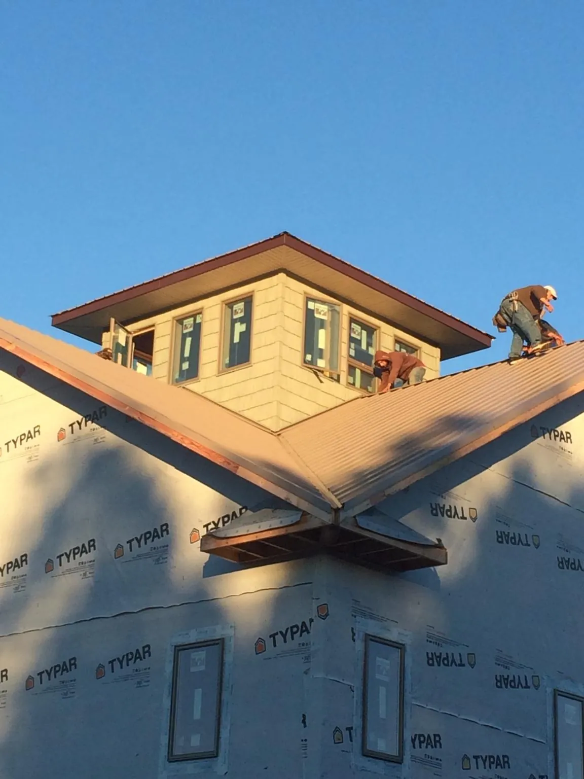 Roofers working around a rooftop cupola on a new metal roof at sunset — Roof Waterproofing in Lincoln City by Roofing Brothers